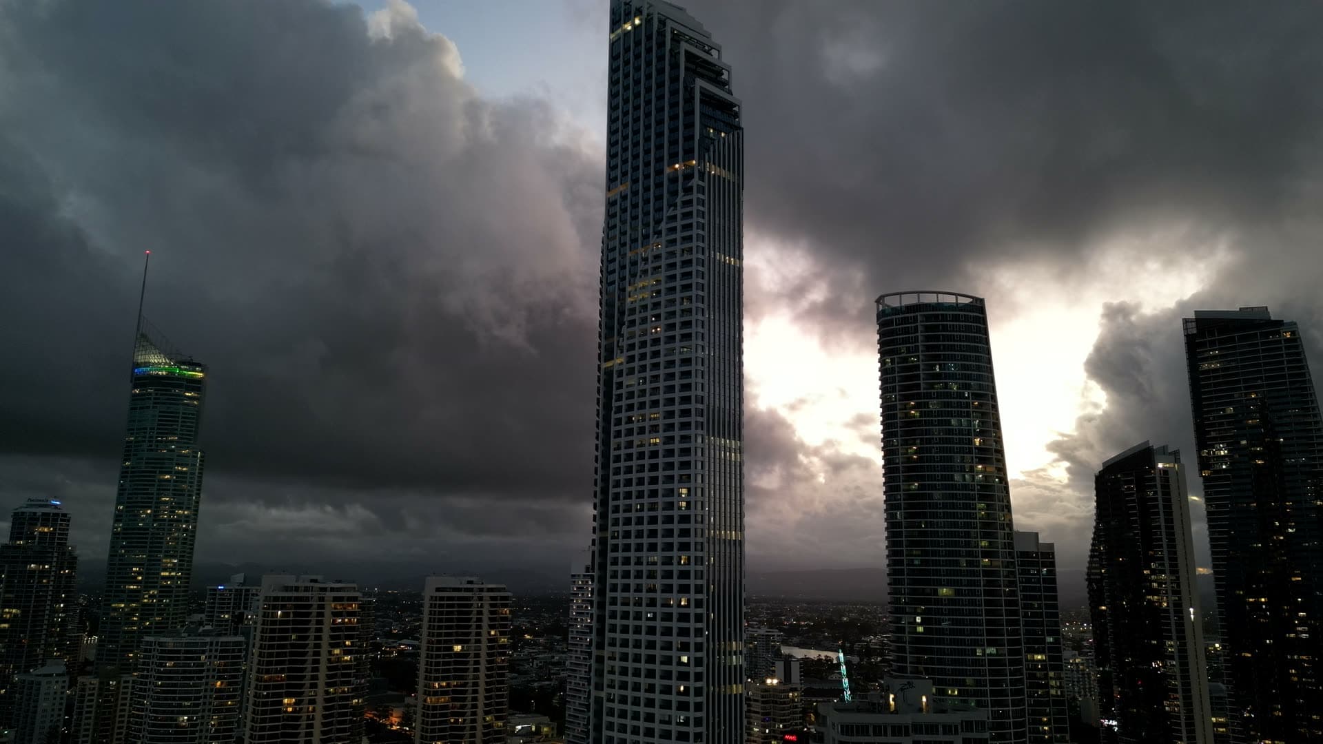 Gold Coast high-rise accommodation towers against a dramatic, cloud-filled sky at dusk.