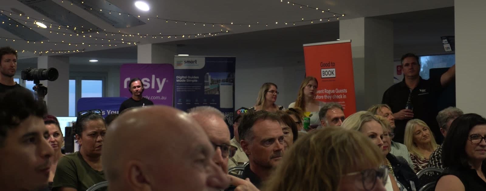 A full function room at the inaugural Beyond Management Rights event, with guests seated in front of exhibitor banners.
