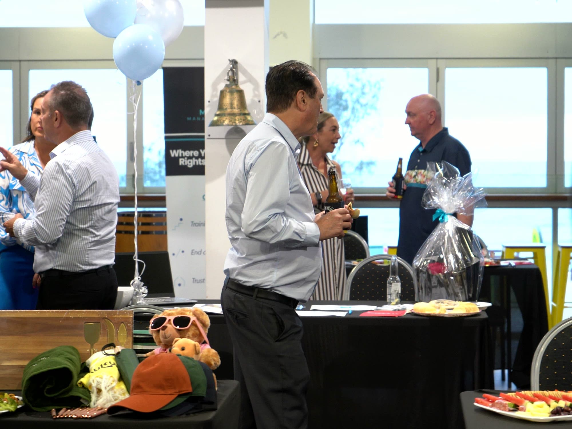 Exhibitor tables with balloons, gifts and guests talking across the function room.