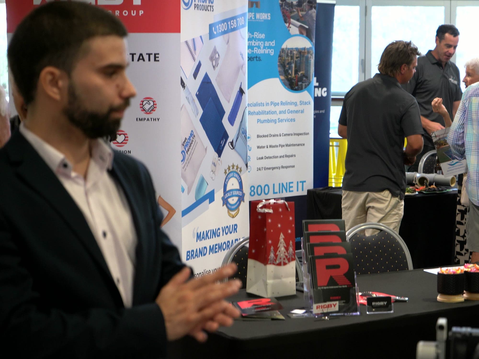 A guest in a suit talking at an exhibitor stand as the room fills up behind him.