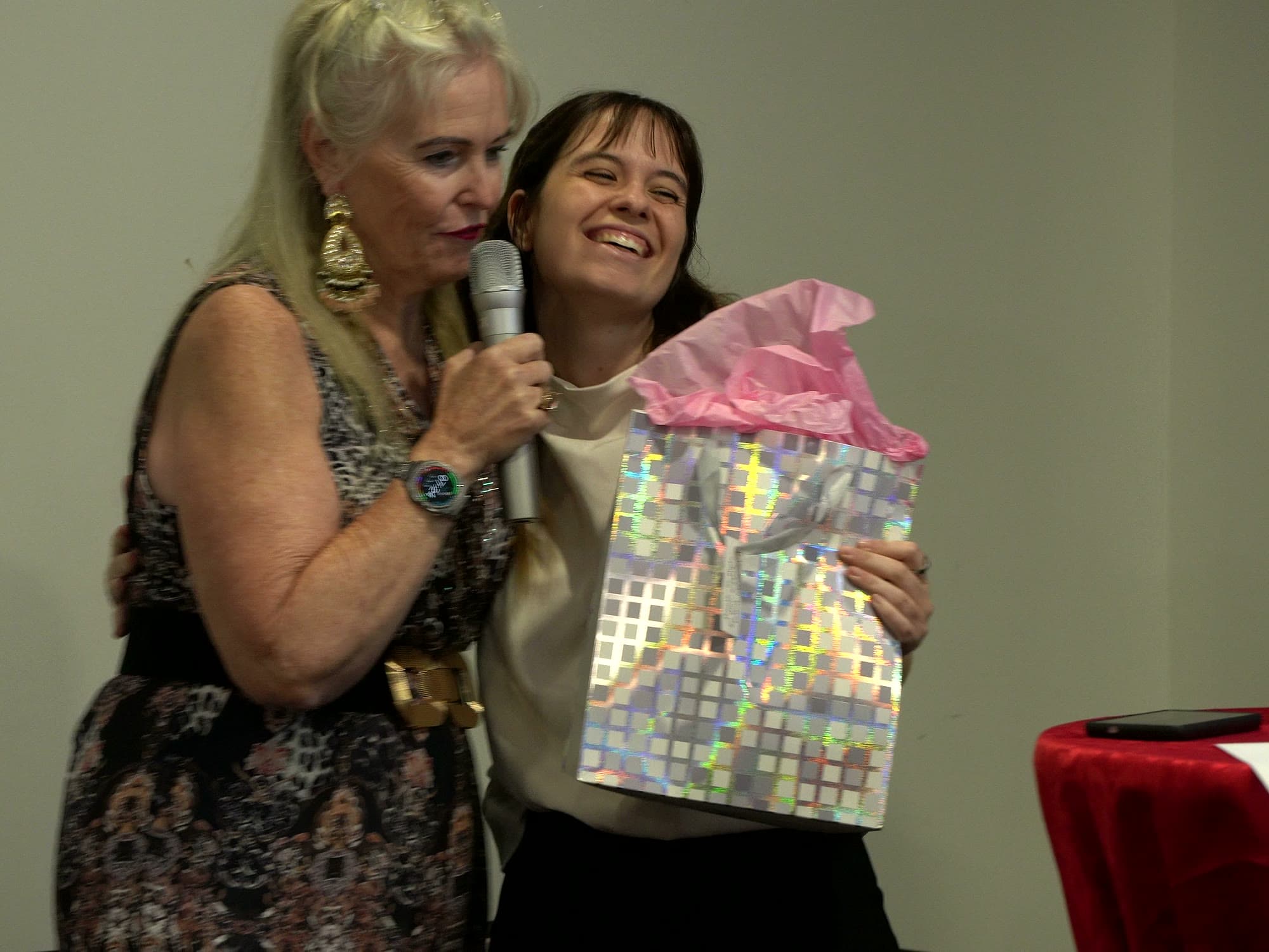 Marion Simon hugging a smiling prize winner who is holding a gift bag during the prize draws.