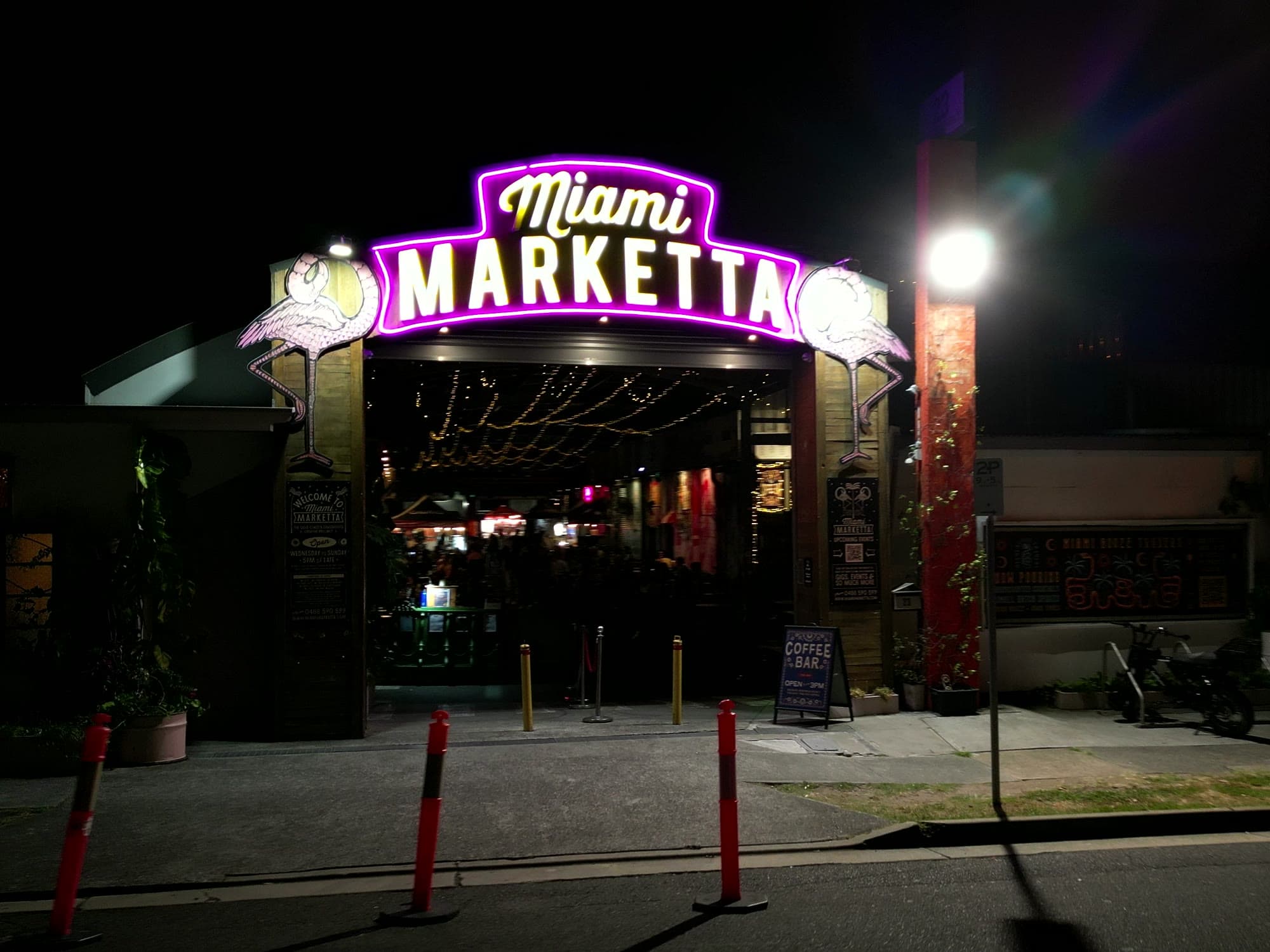The Miami Marketta neon archway and entrance at night, with festoon lights glowing inside.